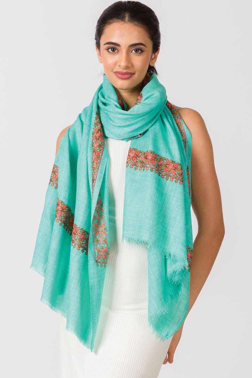 Trebor Style Taisha shawl in teal with intricate peach, pink, and green hand embroidery worn by a woman