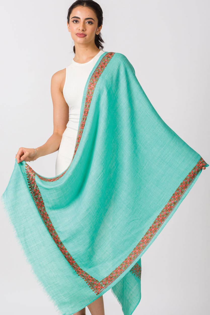 Trebor Style Taisha hand embroidered wool blend shawl in teal with a floral peach and green border on a model