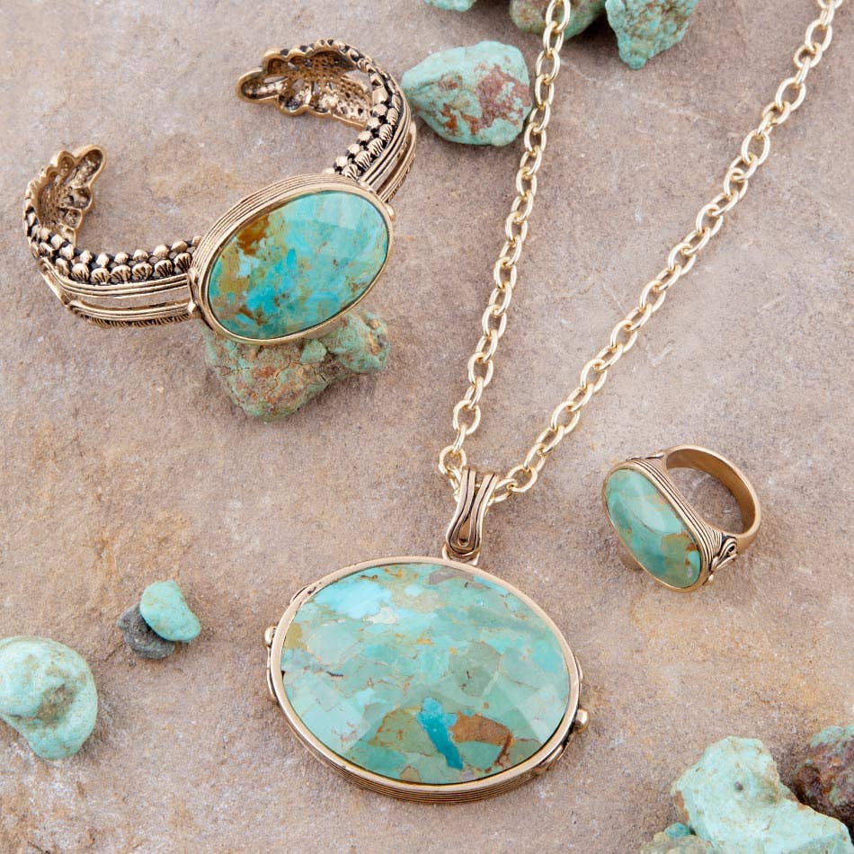 Trebor Style turquoise jewelry set including a long golden chain necklace, cuff bracelet, and ring on stone surface.