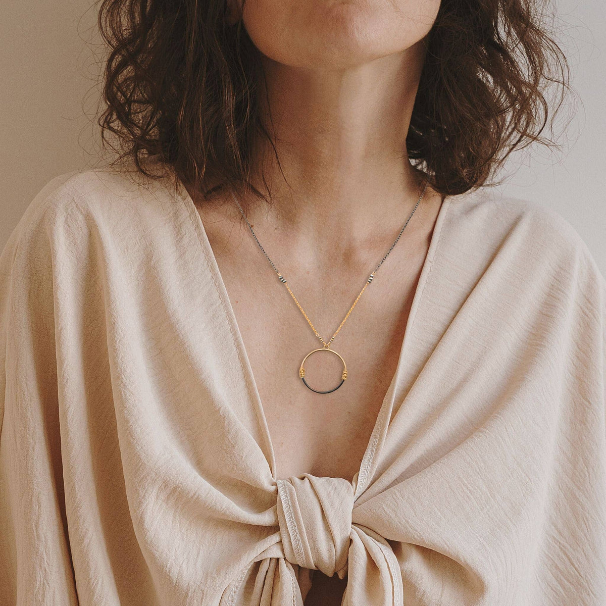 Trebor Style two-tone circle pendant necklace featuring gold-filled and oxidized silver wire-wrapped mixed metal design