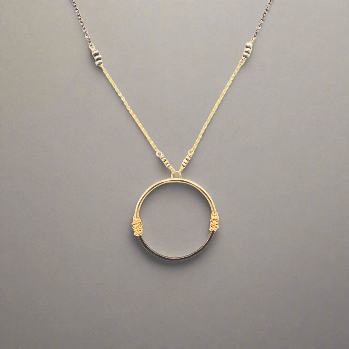 Trebor Style two-tone circle pendant necklace with 14K gold-filled and oxidized sterling silver wire-wrapped detail.