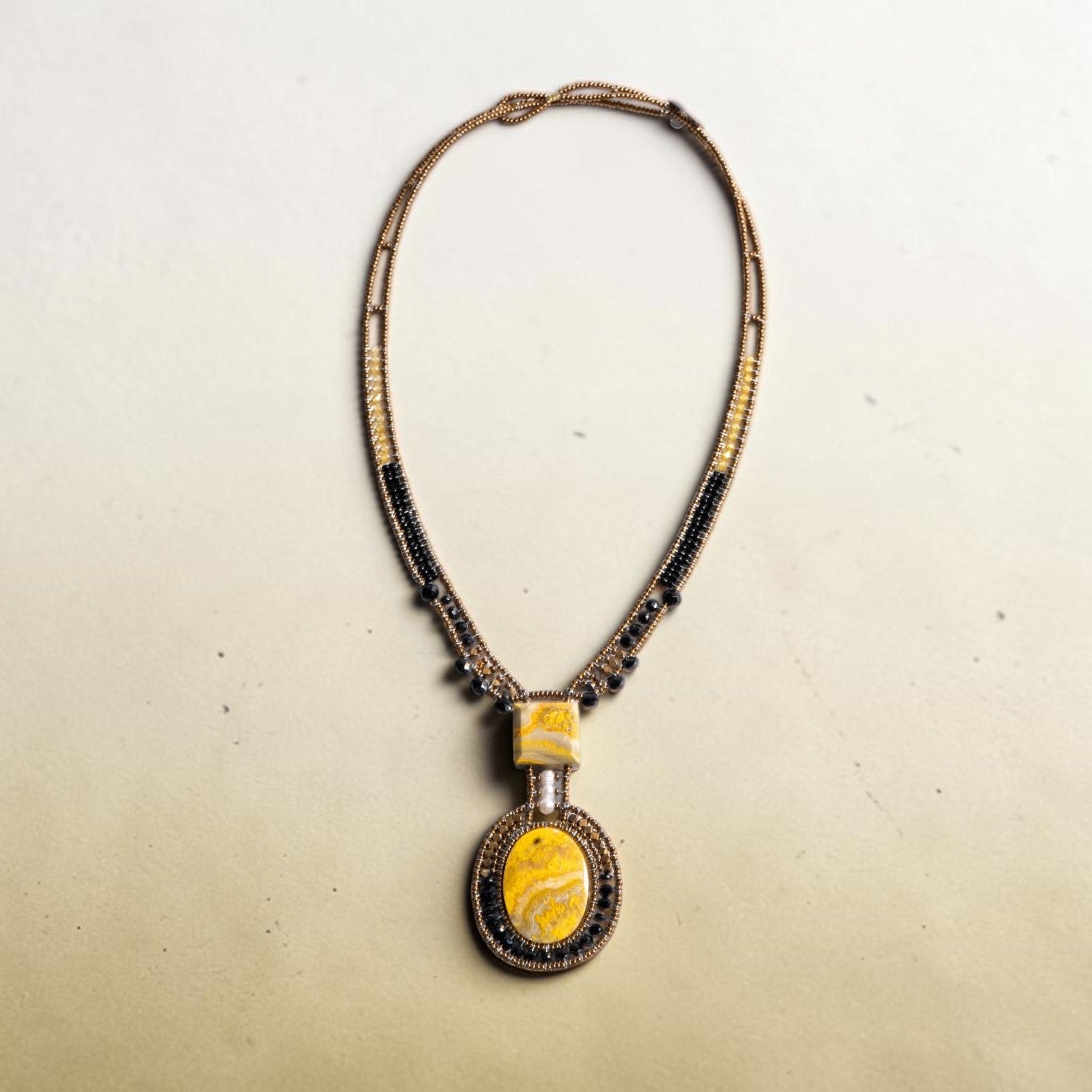Trebor Style artisan statement necklace featuring a yellow jasper pendant with bronze, gold, and black glass beads.