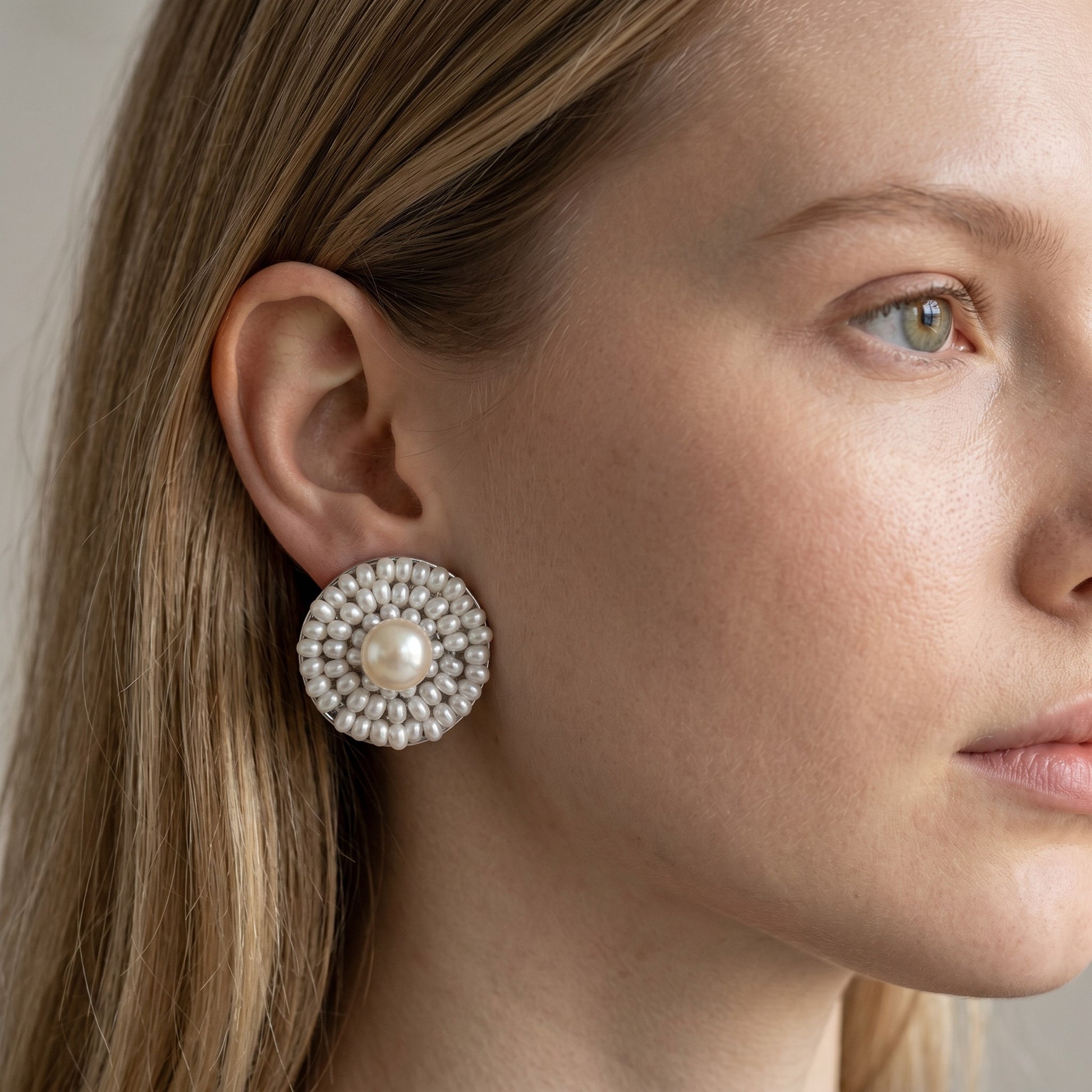 Trebor Style Ziio white freshwater pearl button earring framed by Murano glass beads on a model
